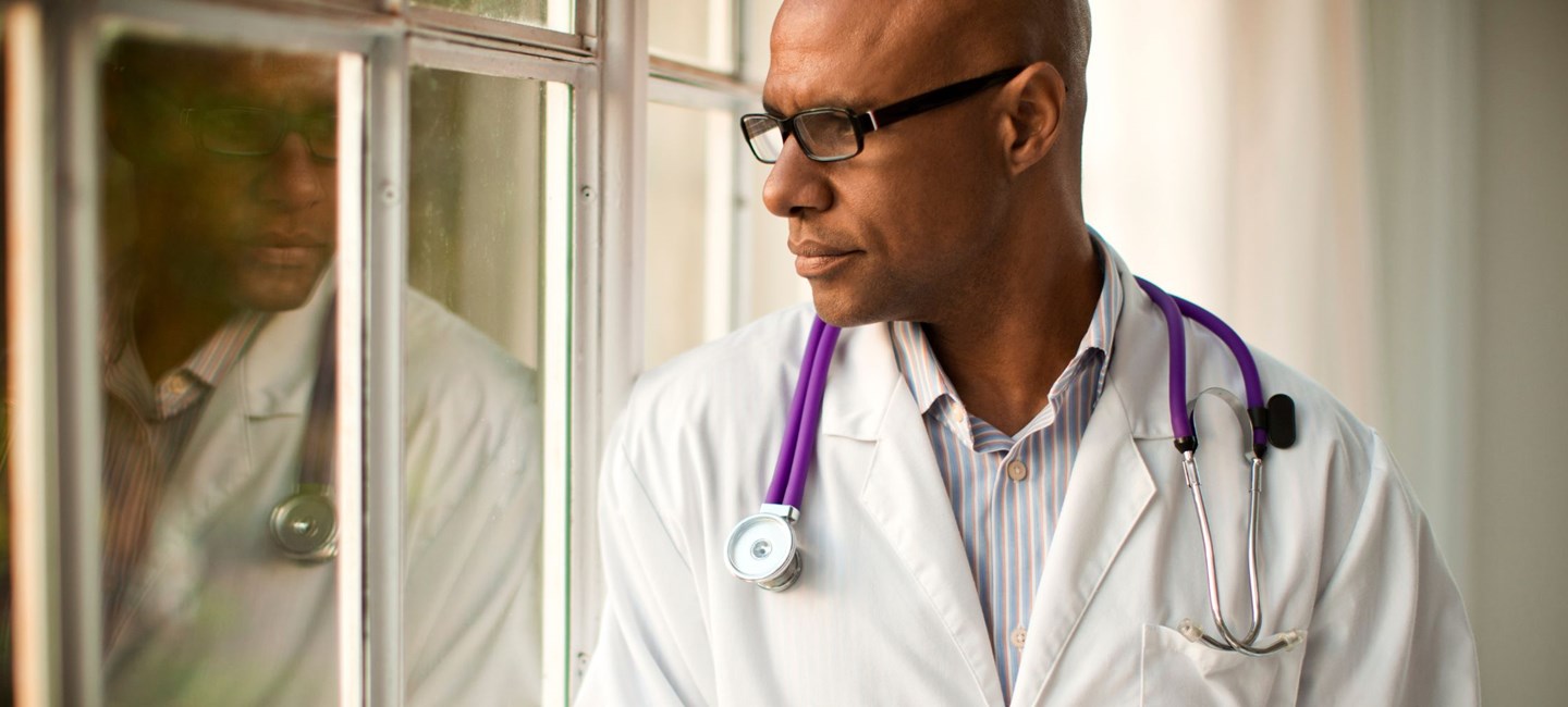HCP looking out of a window with a pensive look on his face